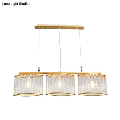 Gold-toned postmodern rod island light with three cylindrical glass shades and crystal rods for dining room island lighting