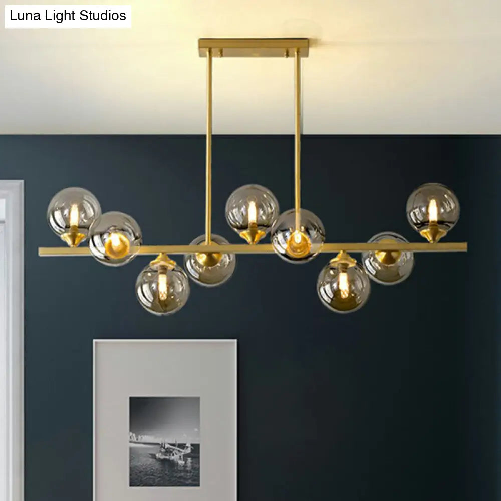 مصباح معلق على شكل كرة زجاجية كهرمانية بلمسة نهائية ذهبية من DecorBites™ بتصميم ما بعد الحداثة لإضاءة الطاولة