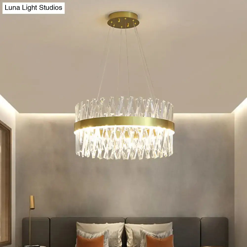 A modern pendant light with a gold finish and clear k9 crystal prisms featuring a circular geometric fixture width