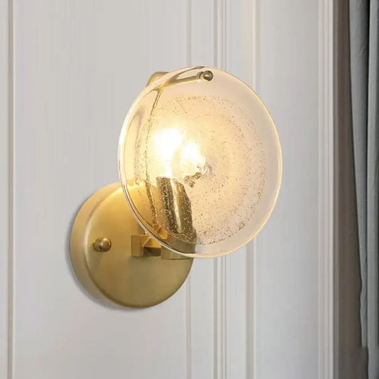 Postmodern gold metal wall sconce with frosted glass shade featuring subtle internal bubbles for bedroom light