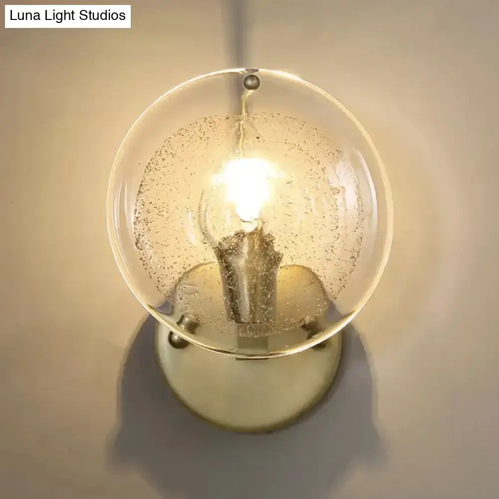 Postmodern gold metal wall sconce with a warm amber frosted clear glass shade for bedroom lighting