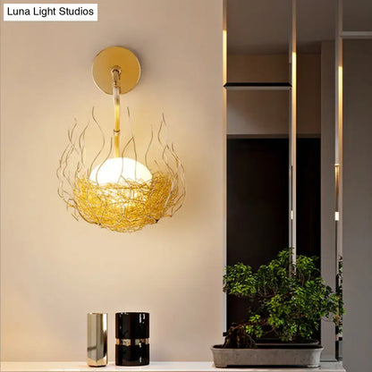 Postmodern gold nest globe glass wall light fixture with spherical bulb in flame-like wire cage for bedroom sconce