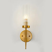 Postmodern gold-toned wall sconce with clear ribbed glass cylinder and slender metallic stem for stairway lighting