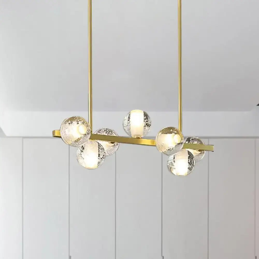 Gold-toned modern chandelier with six clear textured glass globe bulbs featuring seeded crystal suspension ideal for dining rooms