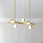 Gold-toned modern chandelier with six clear textured glass globe bulbs featuring seeded crystal suspension ideal for dining rooms