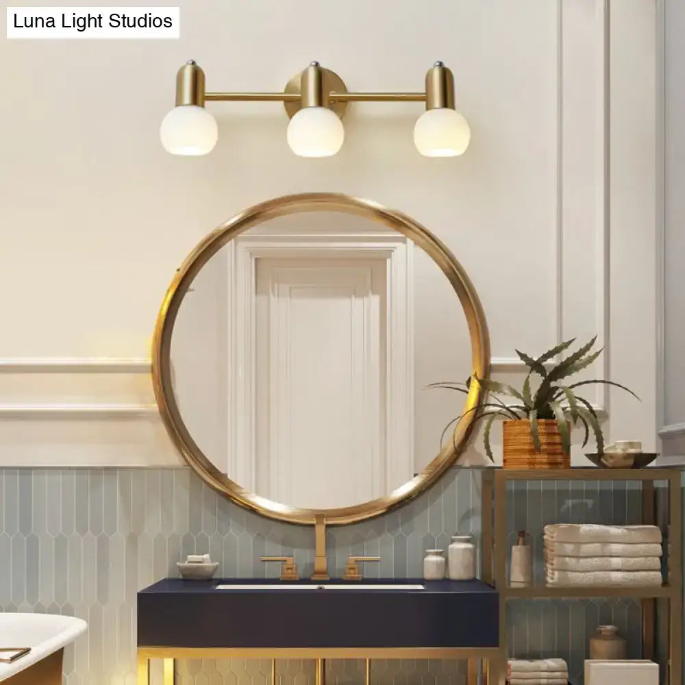 Postmodern gold-toned wall-mounted milk glass vanity light with three frosted dome milk glass globe bulbs bathroom sconce