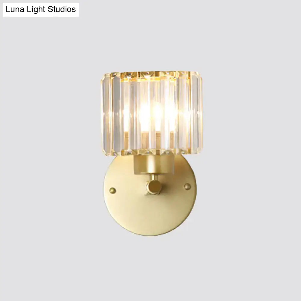 A modern wall lamp with a gold-finished metal base and a prismatic crystal shade for bedroom use