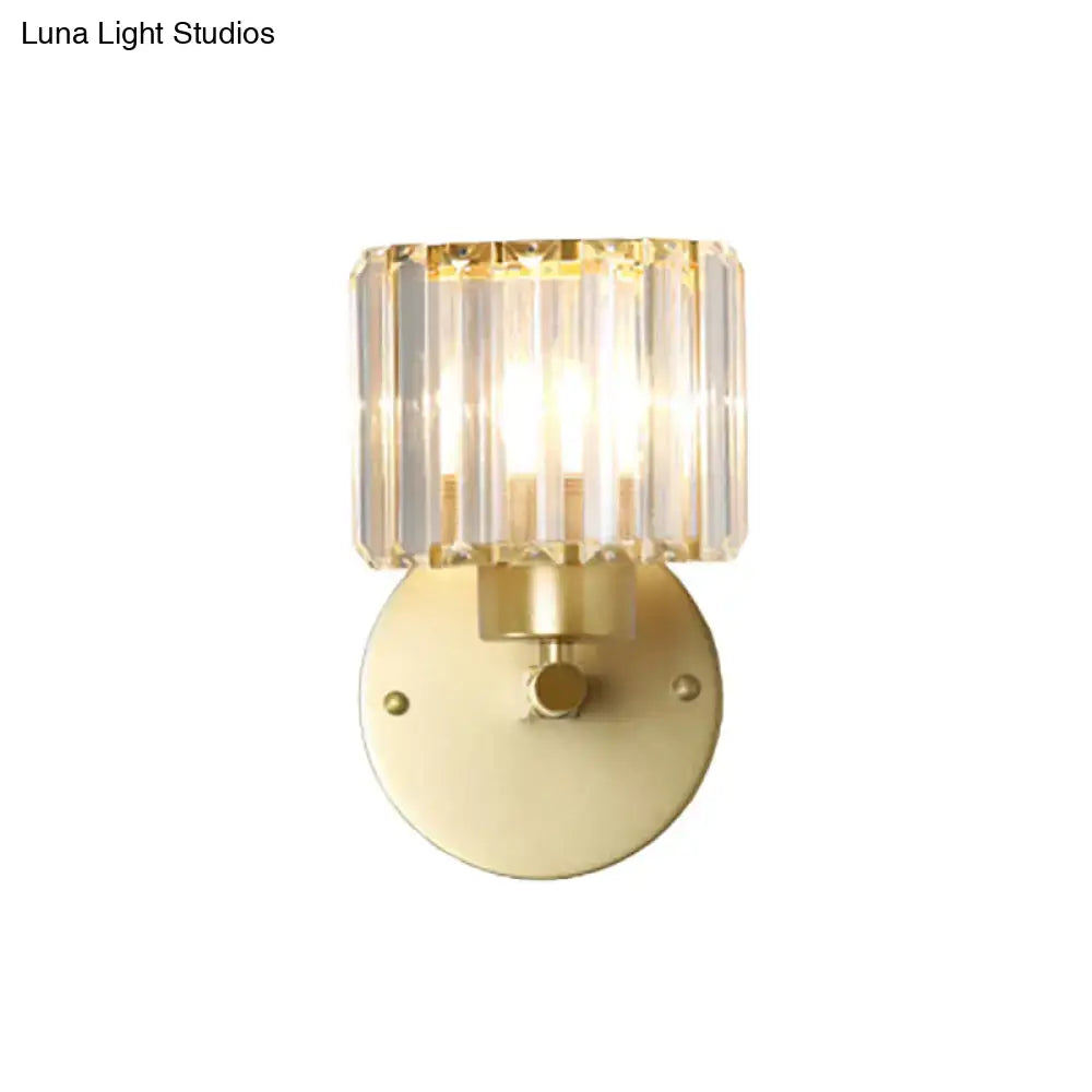 A modern wall lamp with a brushed brass base and a prismatic crystal shade designed for bedroom lighting