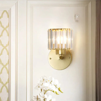 Postmodern gold wall lamp with prismatic crystal shade featuring a cylindrical crystal design for bedroom sconce lighting