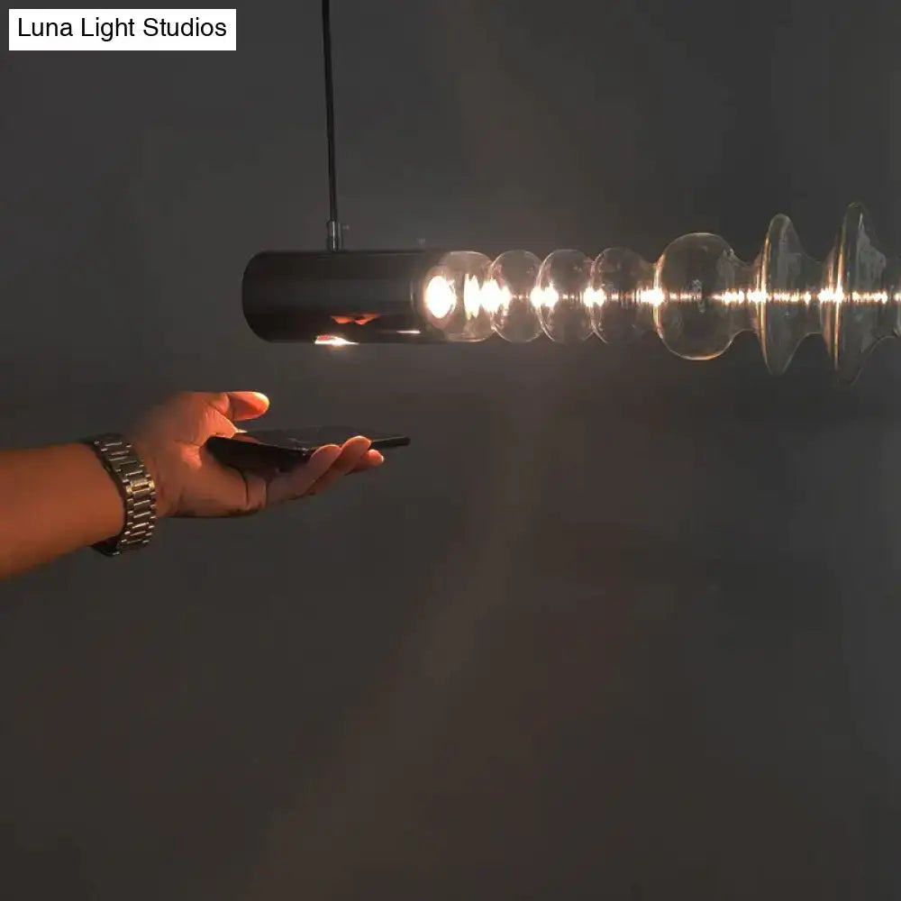 Black cylindrical postmodern lights luxury pendant with clear spiral glass segments emitting warm illumination for restaurant use