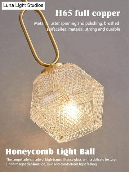 A postmodern luxury led wall lamp with a hexagonal honeycomb glass light ball and brushed brass copper fixture