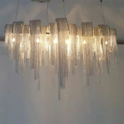 Decorbites postmodern silver lobby chandelier features an arch aluminum chain with cascading glass prisms and 220v-240v 110v-120v compatibility