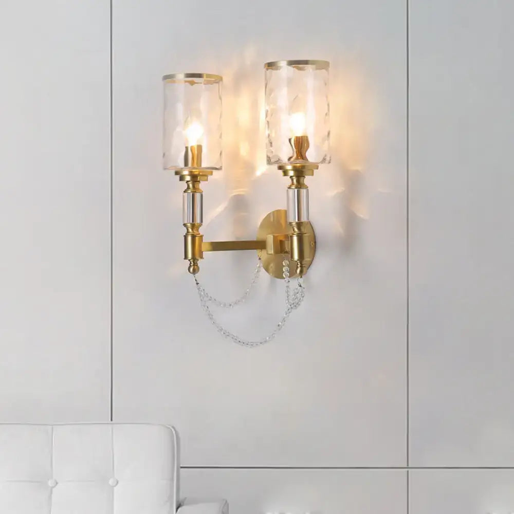 Postmodern water glass brass wall light with gold-toned sconce, two clear textured glass shades, and crystal chain detail
