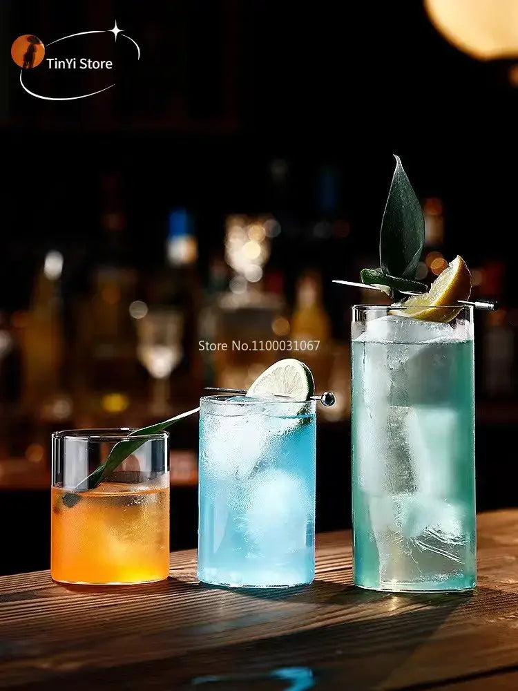 Three tall clear glass highball cups filled with colorful drinks and garnished with lime and leaves in a highball cup set