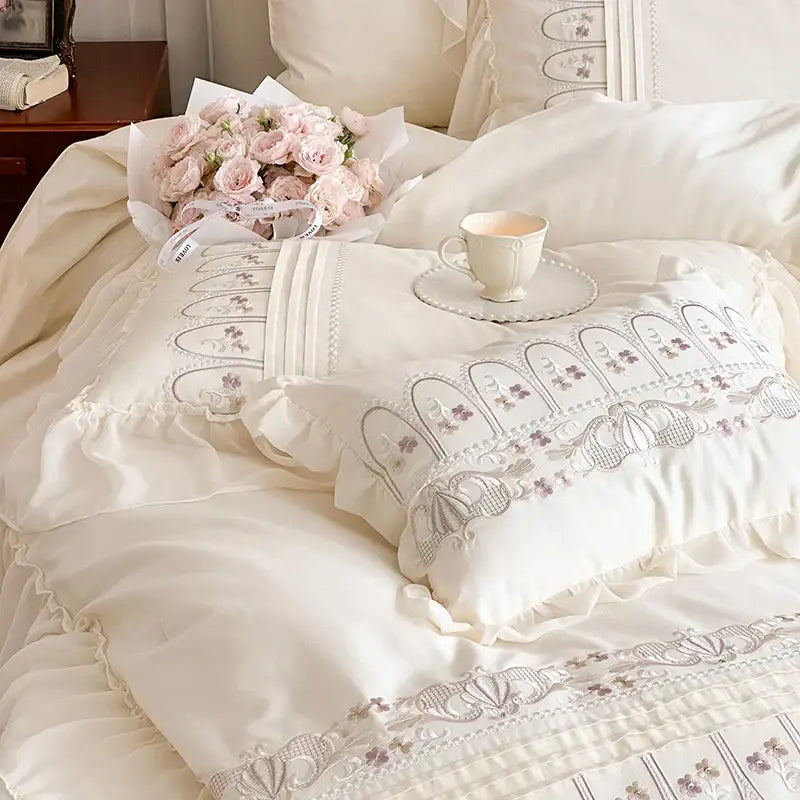 Cream-colored pillow with delicate lavender decorbites flowers embroidery and ruffled edges in princess wedding bedding set