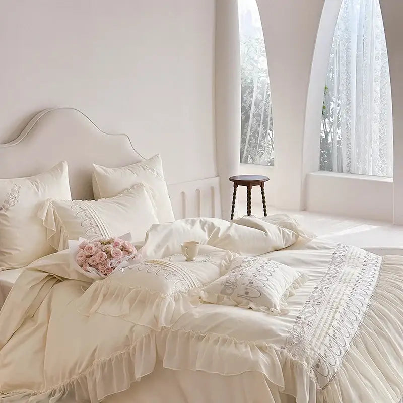 Cream-colored princess wedding bedding set with layered ruffles lace trim and decorbites flowers embroidery detailing
