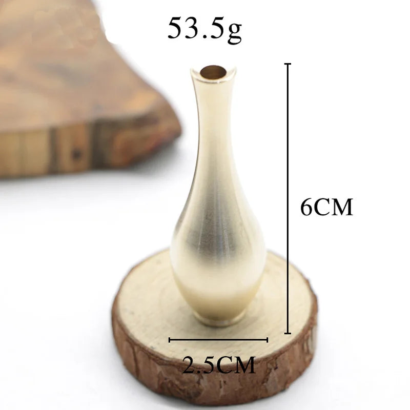 A slender metallic gold-toned pure copper vintage vase with tapered neck on a rustic wooden slice for home decoration