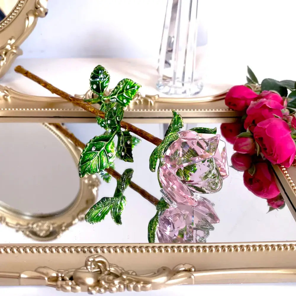 Delicate pink crystal rose hair accessory with green enamel leaves and brown stem paired with purple gold rose figurine