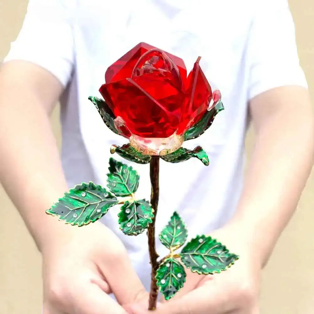 A vibrant red crystal rose figurine with green enamel leaves and gold-toned stem held in hands for living room decor