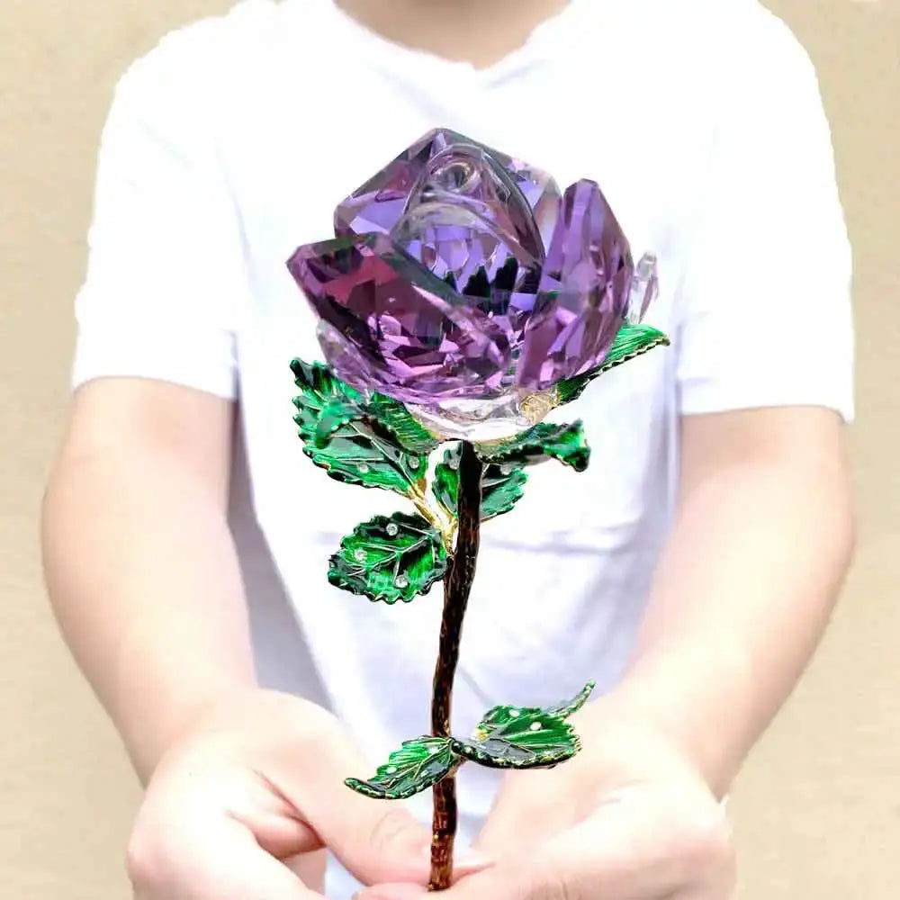 A sparkling purple crystal rose figurine with green enamel leaves and dark stem held gently in hands for living room decor