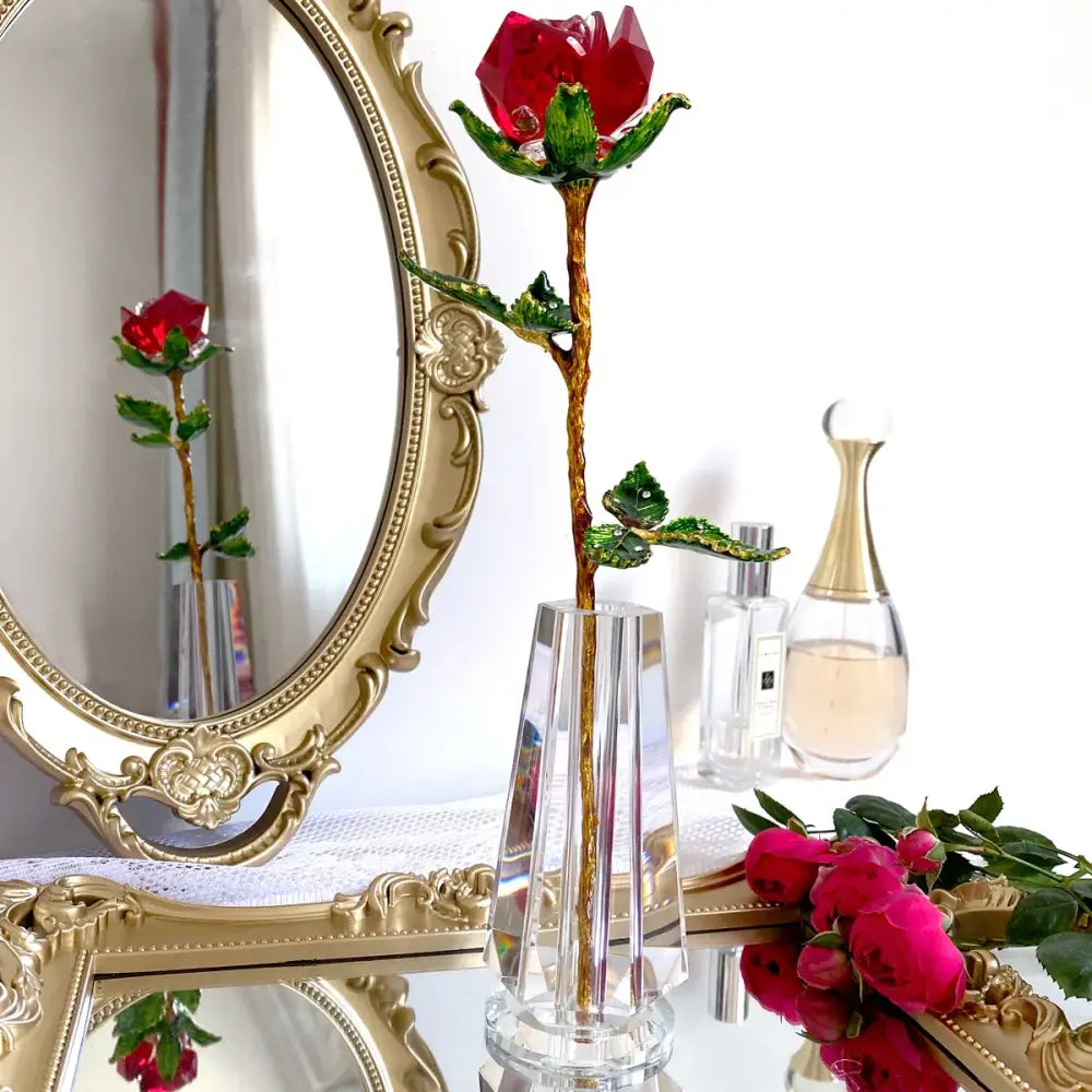 A sparkling red and gold crystal rose figurine with green leaves displayed in a clear crystal vase for living room decor