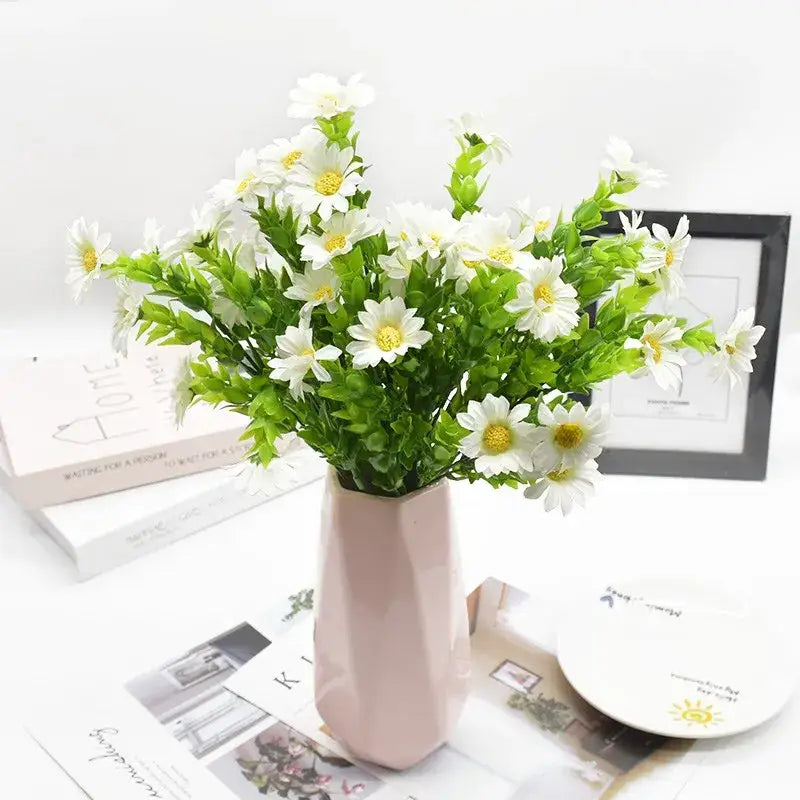 A daisy bouquet green featuring artificial white daisies with yellow centers in a pink geometric ceramic vase