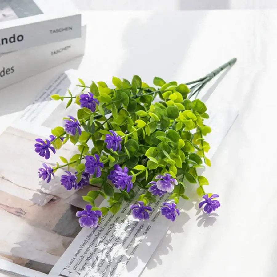 A cluster of purple decorbites artificial eucalyptus plant with green leaves arranged on a white surface for decor