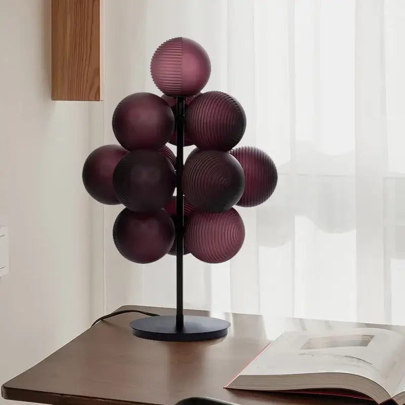 A modern decorbites grape chandelier table lamp with deep purple ribbed glass spheres on black metal stand