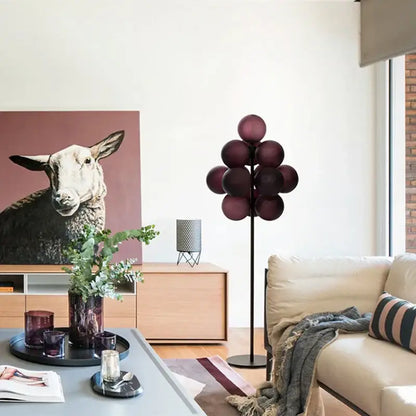 A modern floor lamp with deep burgundy glass spheres on a black metal stand in a decorbites grape chandelier design