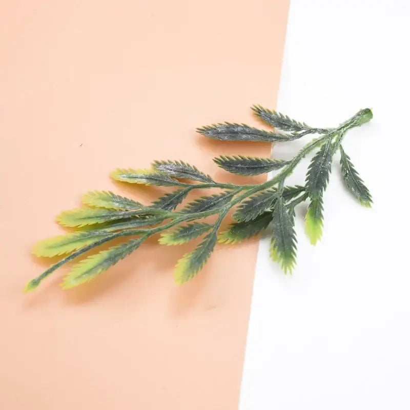 A delicate artificial leafy branch with serrated edges in yellow to dark green plastic from decorbites 10pcs plastic grass set