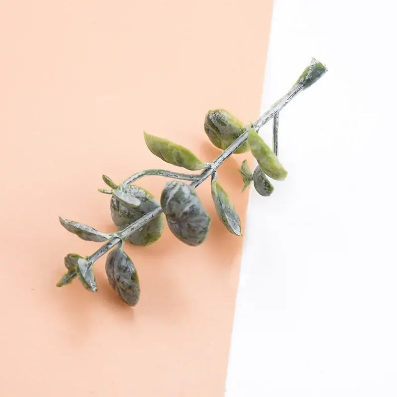 A delicate artificial eucalyptus branch with muted green leaves and silver-toned stem from decorbites 10pcs plastic grass decor
