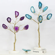 Two decorative purple and teal golden agate tree art piece sculptures with gold-toned branches on marble bases