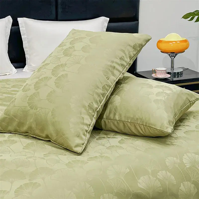 Pair of sage green silk pillowcases with subtle ginkgo leaf pattern complementing a purple zebra print satin duvet cover set