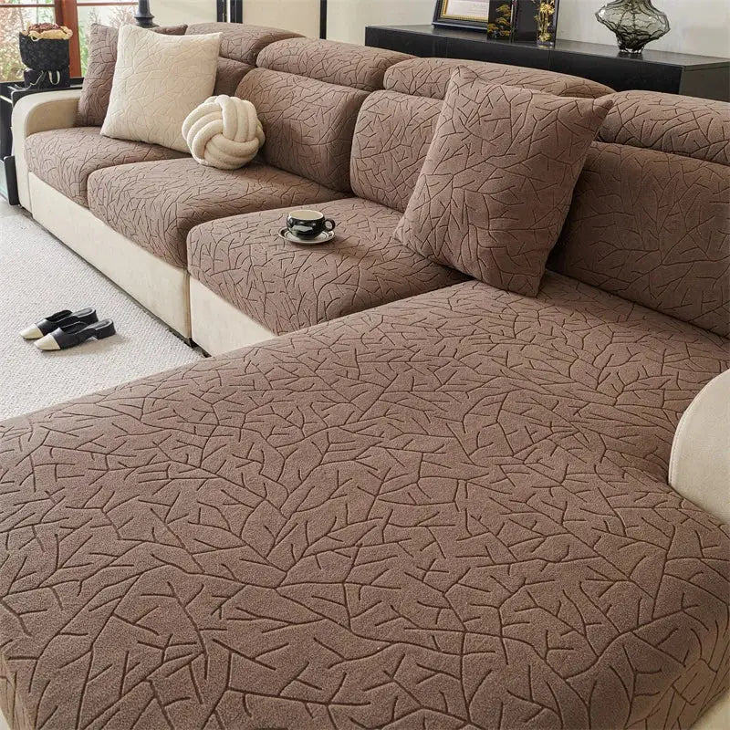 Quilted beige elastic sofa cover with brown textured fabric and leaf pattern for living room use