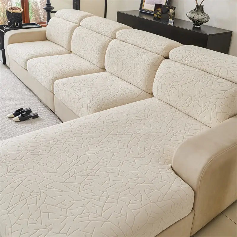 Cream-colored quilted sofa cover with subtle geometric leaf pattern made of elastic fabric for living room use