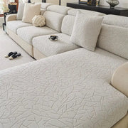 Beige quilted sofa cover with subtle leaf embossed pattern and elastic edges for living room use