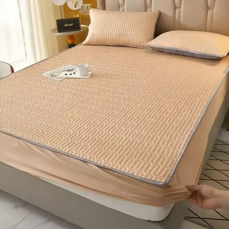 Beige quilted bed pad with geometric pattern and gray piping as part of cooling fitted sheet set for mattress protection
