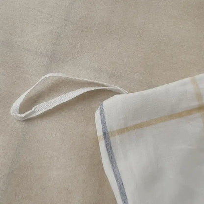 White fabric pillowcase with beige and gray stripes and woven cotton tie from geometric printed bed set
