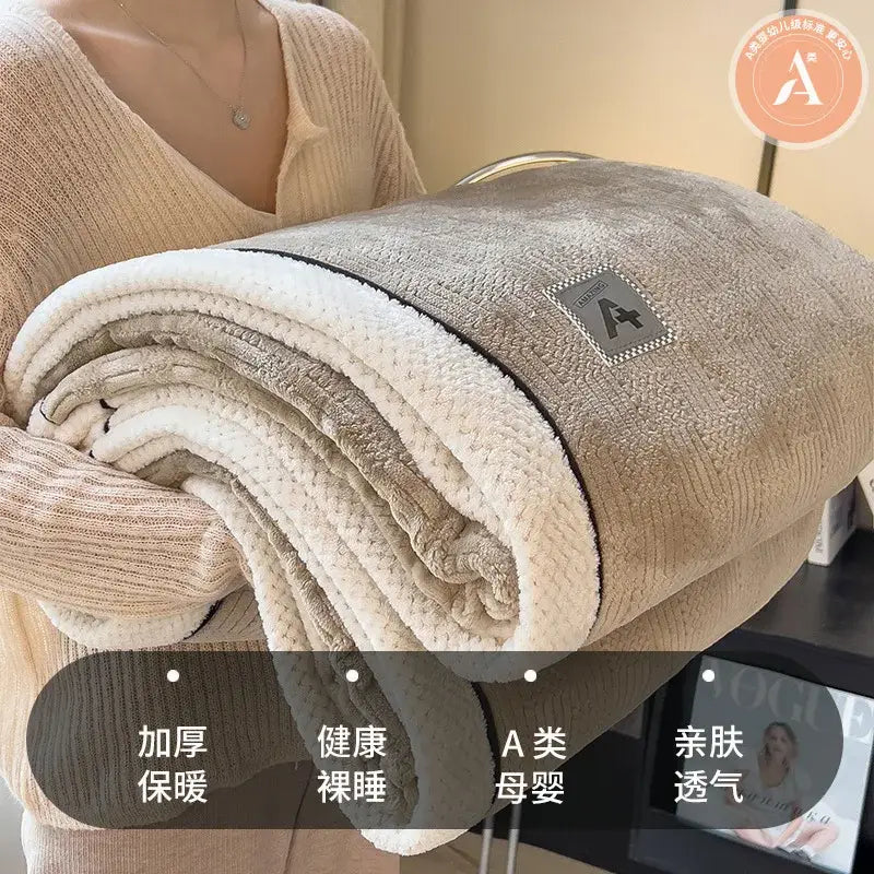 A plush beige and cream quilted blanket with cozy cotton velvet texture and an embroidered logo patch