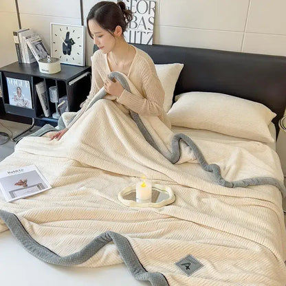 Cream-colored plush blanket with soft textured weave and gray ribbed border made of cozy cotton velvet decorbites plush blanket