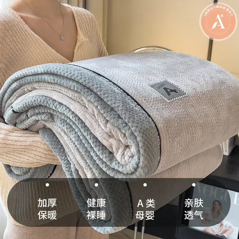 A plush blanket in cream and gray made of decorbites cozy cotton velvet with a soft textured surface and embroidered logo patch