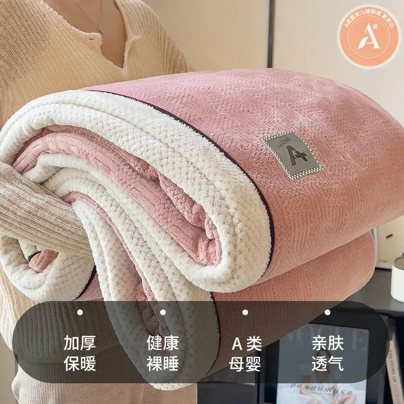 A plush blanket with a soft pink exterior and cream interior in cozy cotton velvet featuring a branded patch