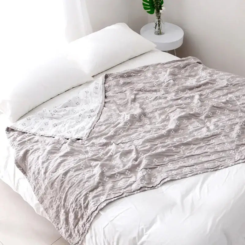 A soft light gray decorbites cotton summer blanket with subtle white floral pattern and gentle textured weave