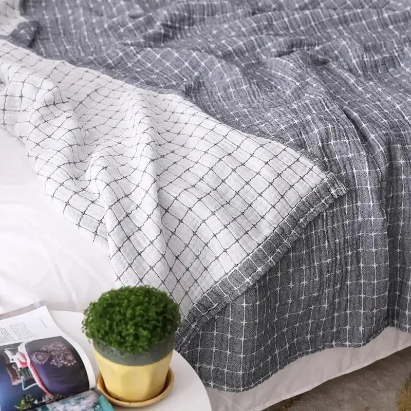 A soft textured gray and white checkered decorbites cotton summer blanket with a subtle ribbed weave for bedroom use