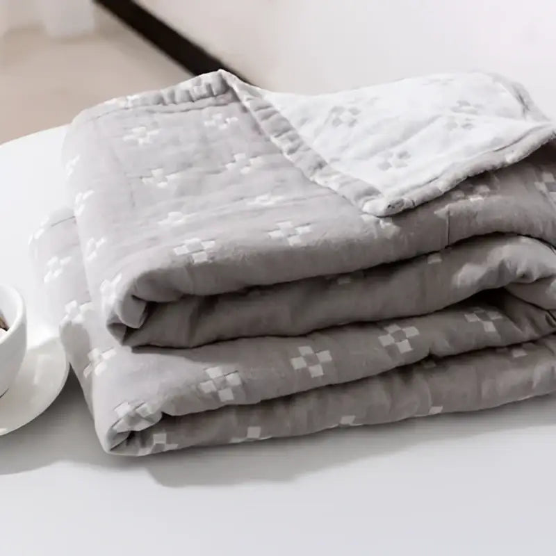 A soft gray quilted decorbites cotton summer blanket with subtle white crosshatch pattern for bedroom use