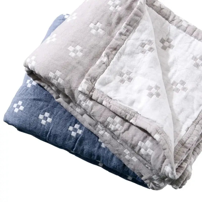 Stacked soft decorbites cotton summer blankets in muted gray and deep blue with quilted crosshatch patterns