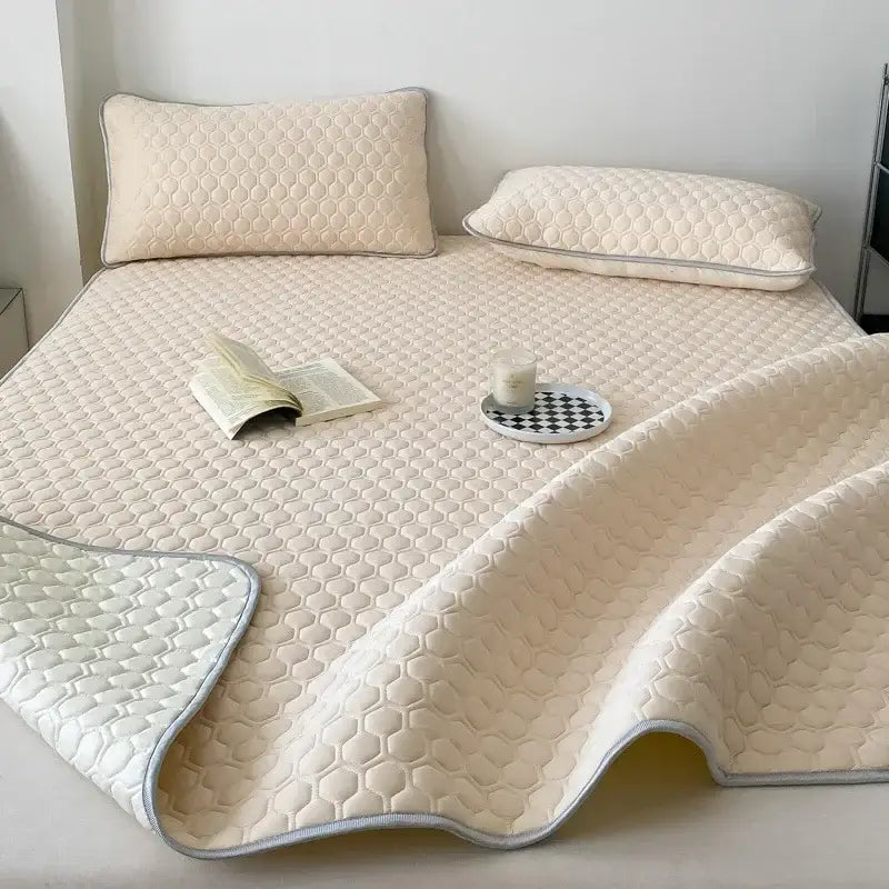 Cream-colored quilted decorbites cooling mat with hexagonal pattern and light gray piping for bedroom bedding set
