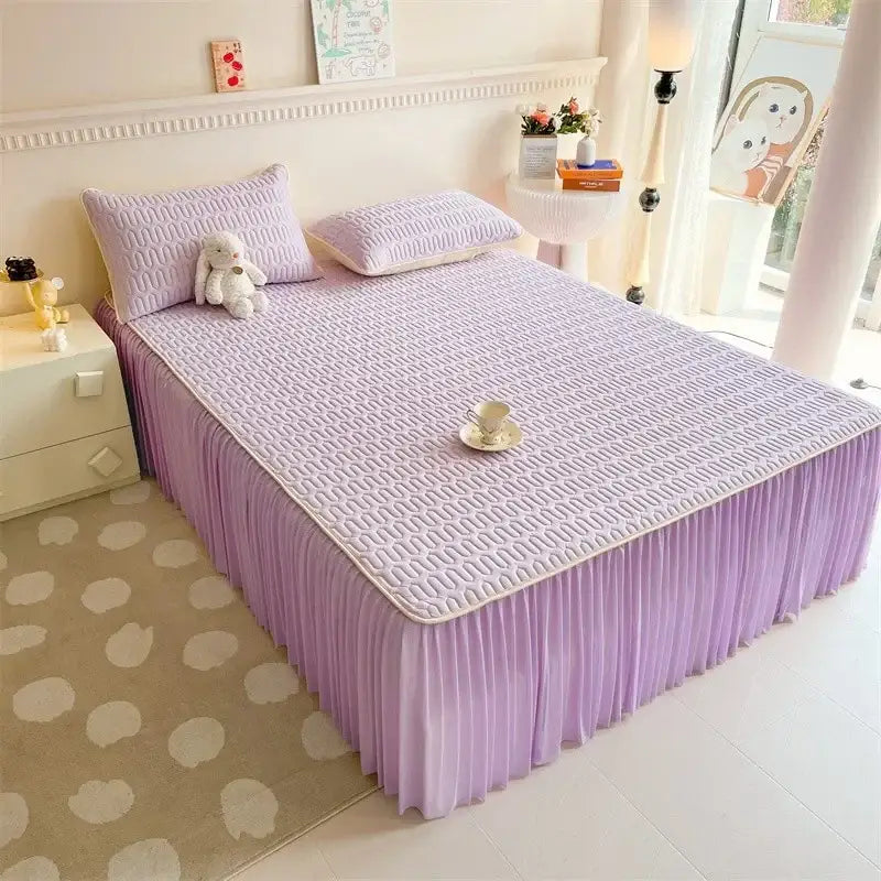 Lavender-colored bed skirt set with pleated fabric and matching quilted mattress pad with silver trim