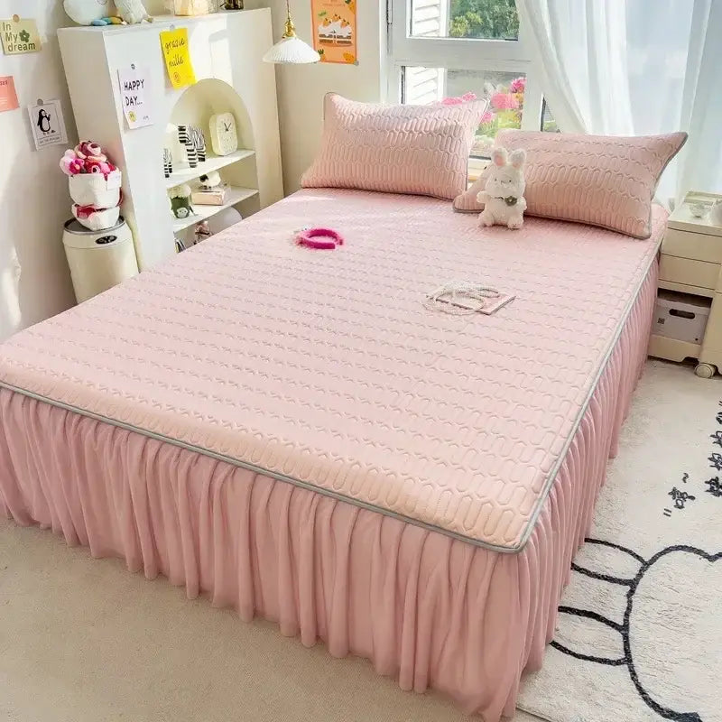 Pink quilted bed skirt set with ruffled skirt and silver trim designed as a bedroom bed pad accessory