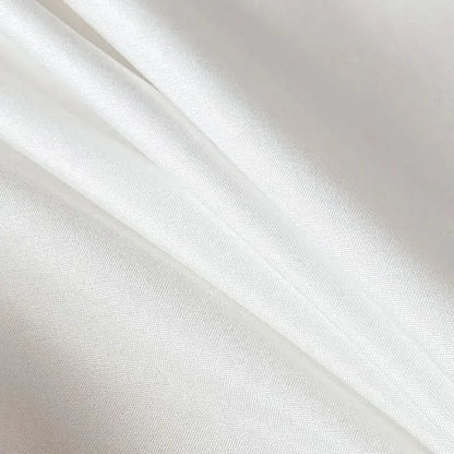 White satin fabric with smooth glossy finish and subtle woven texture on quilted tan duvet cover set for soft bedding